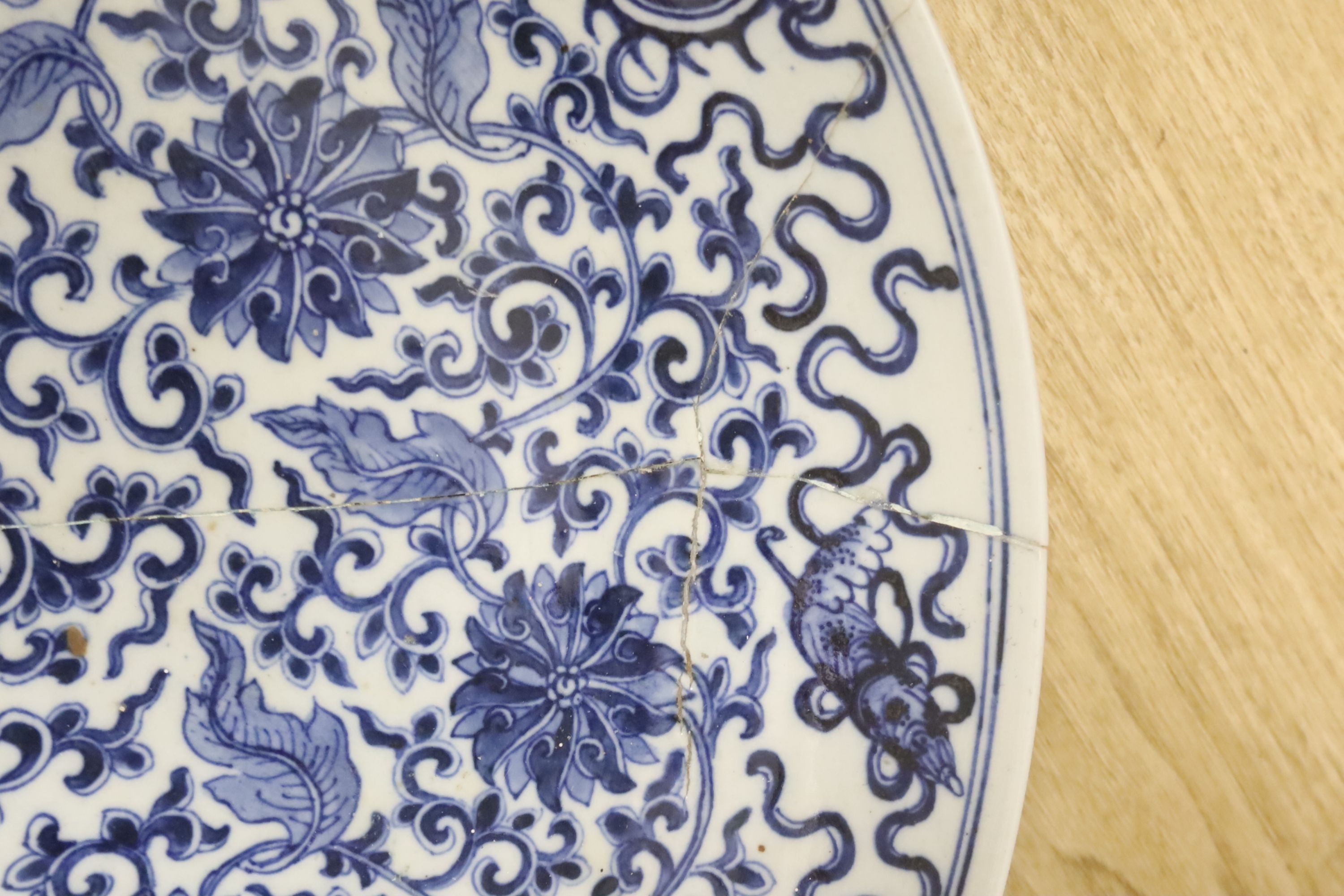 A large Chinese blue and white 'lotus and eight Buddhist emblems' dish, Daoguang period, repaired. 46cm